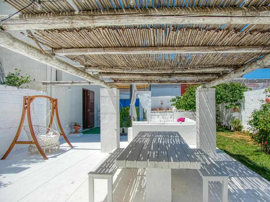 White courtyard with wooden table and pergola at Ideal Rooms